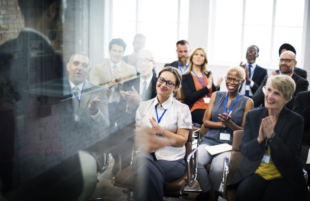 A group of people sitting in front of a glass window.