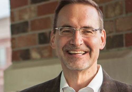 A man with glasses smiling for the camera.