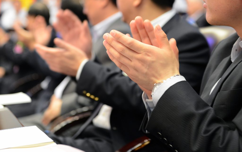 A group of people sitting in front of each other clapping.