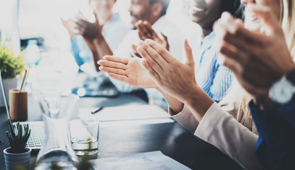 A group of people sitting at a table clapping.