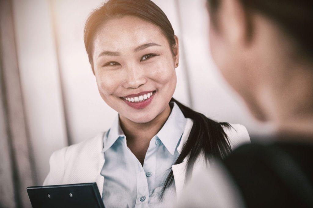 A woman smiles while holding her phone.