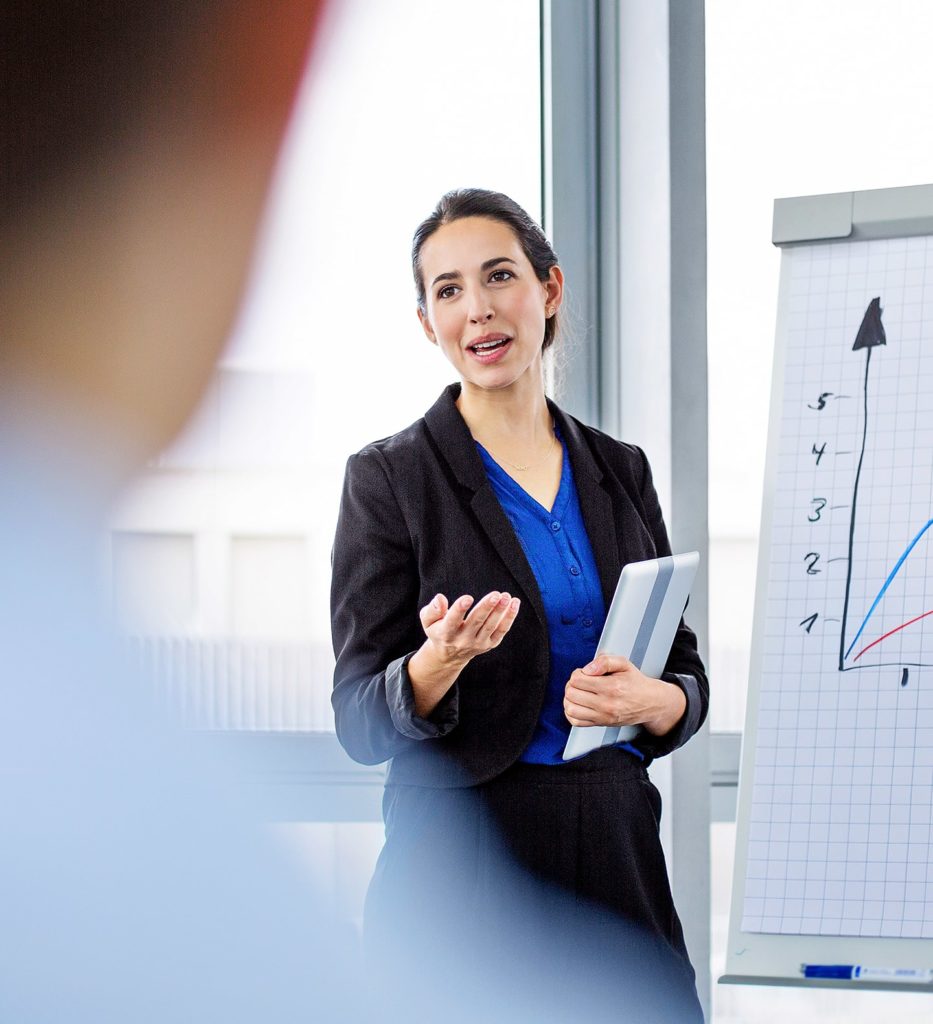 A woman in business attire is giving a presentation.