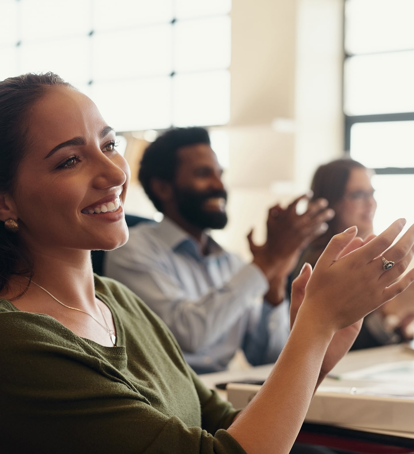 A woman clapping at an event with other people.